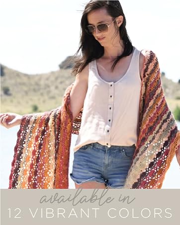 A woman outdoors in an orange, brown, and red crochet shawl.