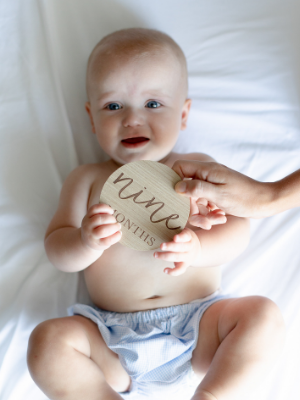 Newborn laying next to One Month milestone card