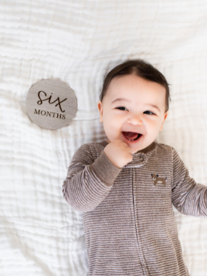 Newborn laying next to One Month milestone card
