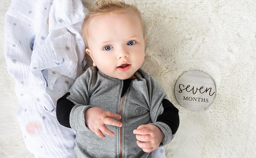 Baby laying next to seven months milestone card