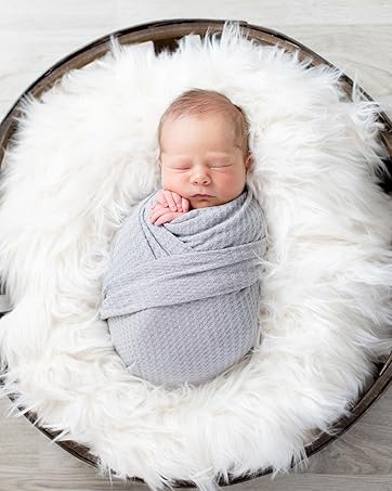 Baby posed in basket with faux furs and posing pillows