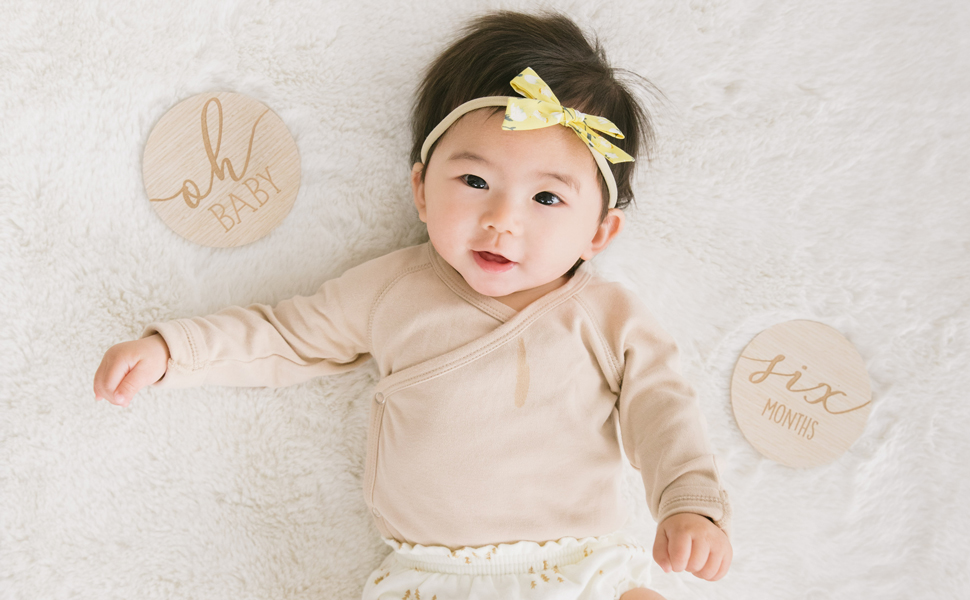 Image of baby laying next to wooden milestone markers for photo