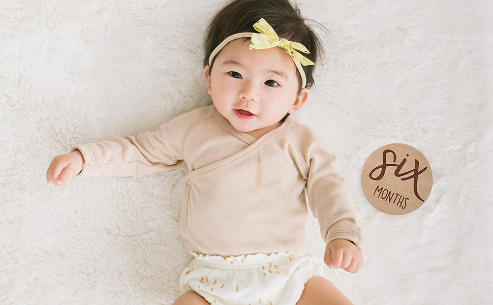Baby laying next to Six Months milestone card