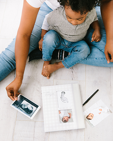Toddler sitting with mom while filling out baby book